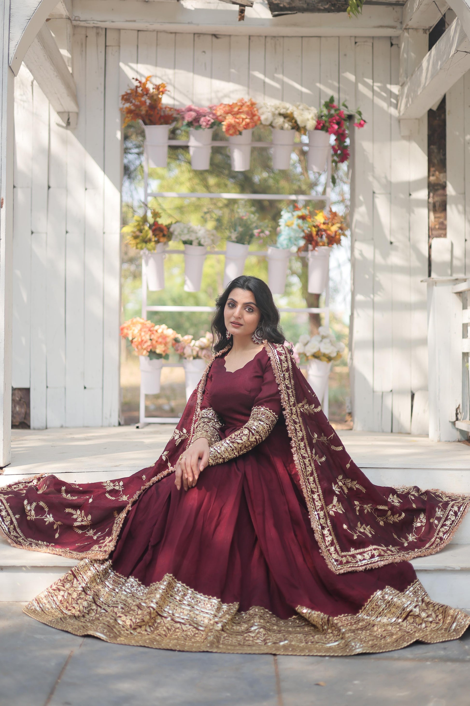 Elegant burgundy designer gown for women with intricate gold embroidery and a flowing silhouette