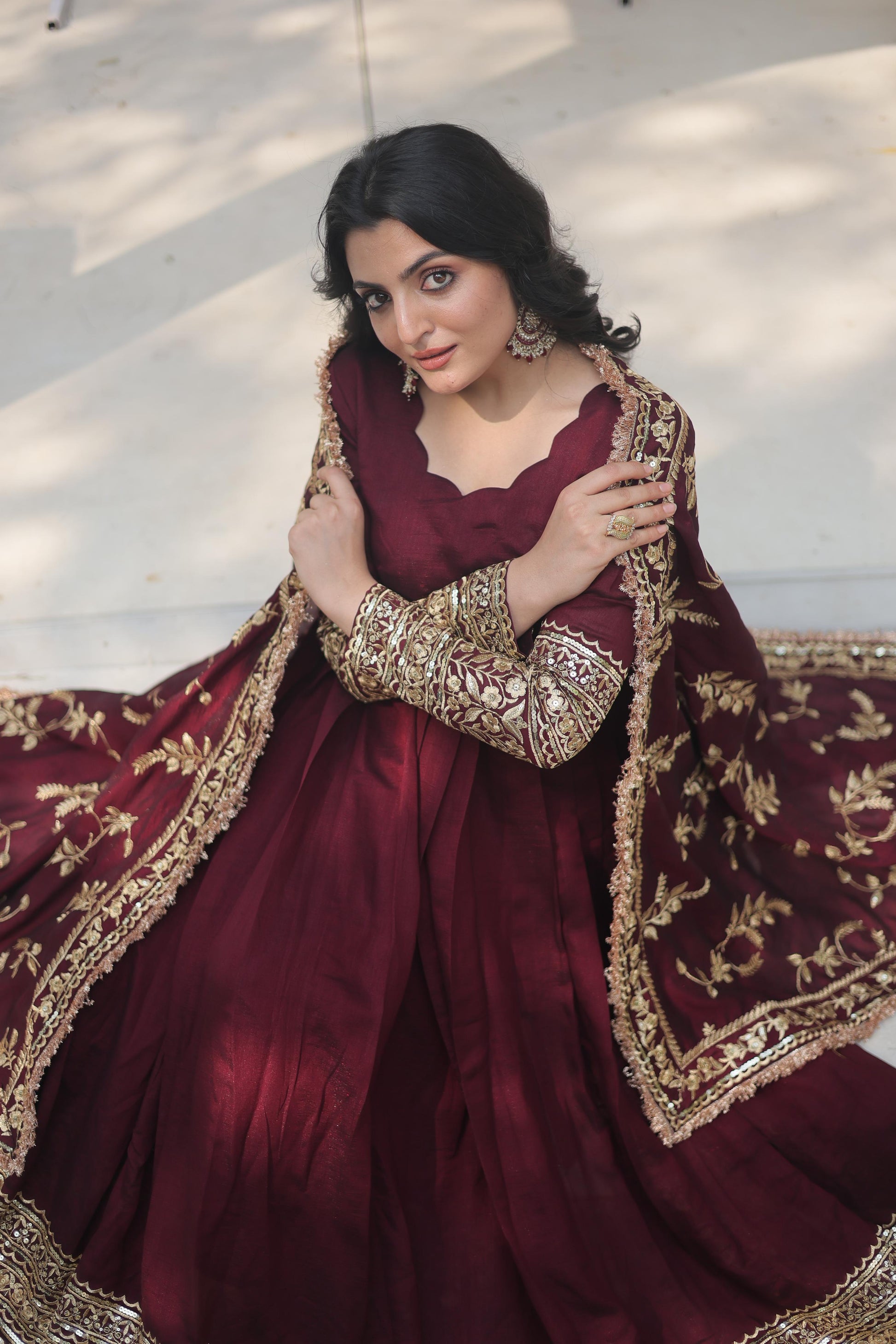 Elegantly styled burgundy designer gown for women adorned with intricate gold embroidery