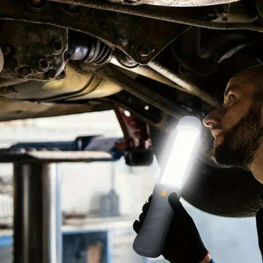 Person using solar rechargeable magnetic lights for detailed vehicle maintenance under a car