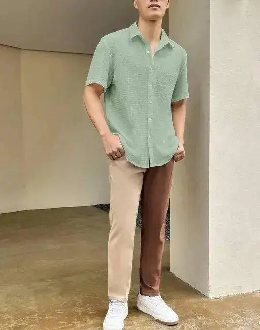 Man wearing light green short-sleeve summer casual shirts for men paired with color-block pants and white sneakers